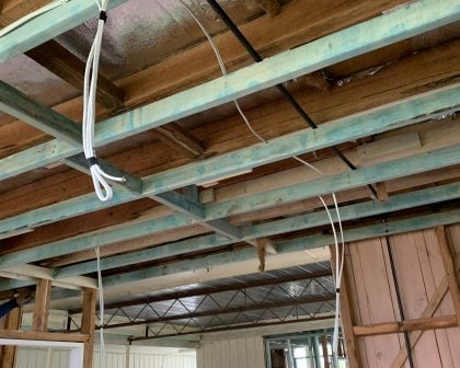 A room under renovation or construction, showing the exposed ceiling and wall structure.