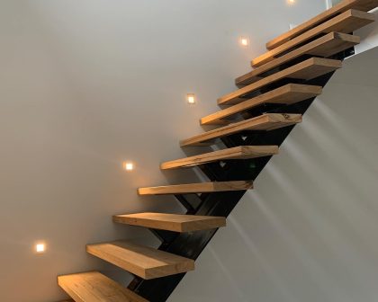 Several square, low-profile LED wall sconces or stair lights are recessed into the wall, illuminating each step and providing accent lighting.